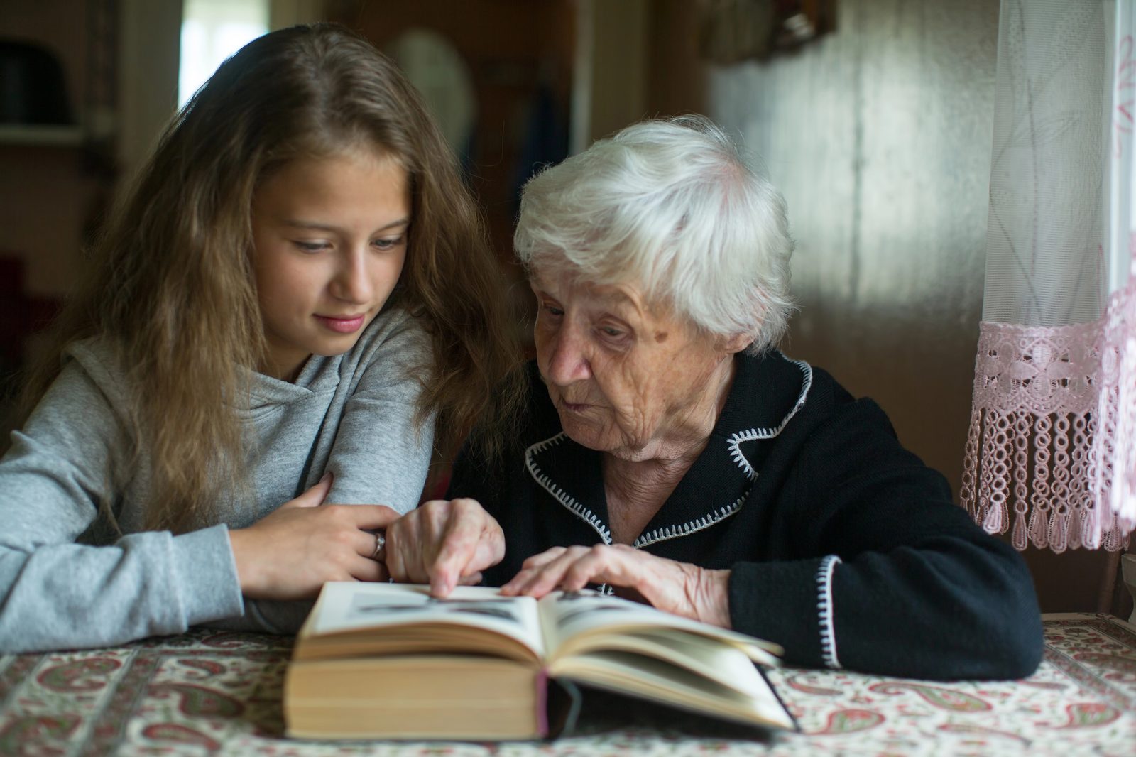 A grandmother and her granddaughter looking through an old family photo album together